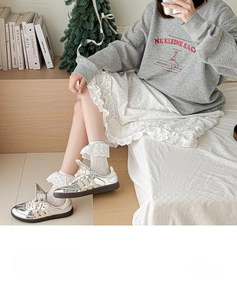 Détail de chaussettes en dentelle blanche portées avec des baskets argentées et un sweat