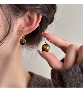 Detailed close-up of tiger eye stone earrings on model showing natural brown chatoyancy