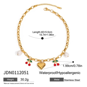 Détail d'un collier en acier inoxydable doré avec perles et breloques cerise et cœur