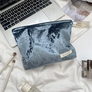 Macro detail of dark blue velvet cosmetic bag with Sozakka brand tag on white fabric