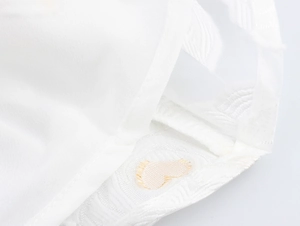 Detail view of the white mesh lace and embroidered jacquard texture on the puff sleeve dress