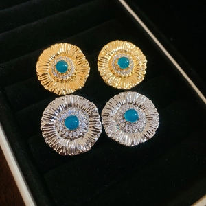 Detailed close-up of gold and silver sunflower stud earrings with turquoise center stones