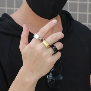 Minimalist rectangular signet rings in silver, gold, and black worn on hand