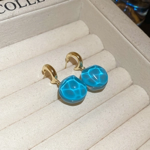 Detailed macro view of blue water-ripple glass drops on golden hook earrings