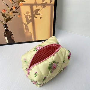 Detail of floral quilted makeup bag with pink rose patterns and checkered lining