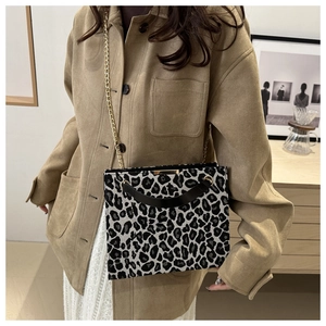 Chic leopard print square bag with gold chain strap and top handle worn by a model