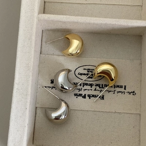 Minimalist C-shaped metal stud earrings in gold and silver finish with high-polish texture