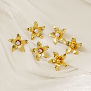 Close-up of gold flower earrings with pearls and crystals on white silk fabric