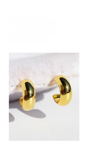 Macro shot of polished gold-plated C-shaped chunky hoop earrings with mirror finish