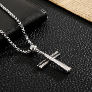 Detailed shot of a silver baseball bat cross pendant on a premium black leather surface
