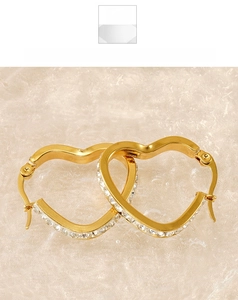 Detail of heart-shaped gold hoop earrings with sparkling rhinestones on fabric