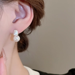 Close-up of minimalist irregular matte silver stud earrings with round white pearl pendant