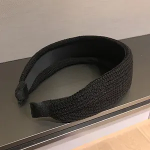 Detail view of wide black knit headband featuring high-density texture and soft ribbon ends