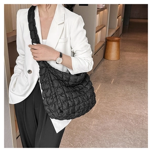Detail view of the large black quilted cloud bag texture on model in minimalist setting