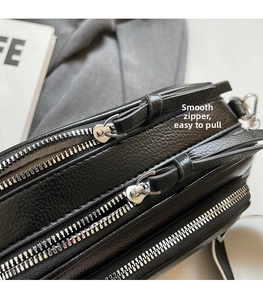 Detail of smooth silver zippers and black lychee texture leather on camera bag