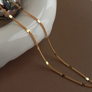 Detail of layered gold titanium steel necklace with flat round discs on ceramic