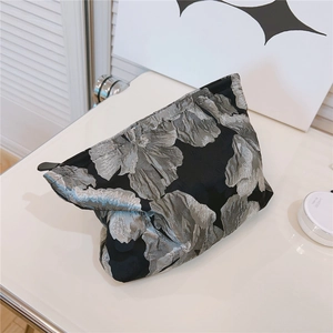 Detailed macro view of black floral jacquard fabric and leather zipper on makeup bag