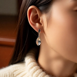 Close-up of polished silver spoon earring on model's ear featuring unique modern design