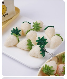 Realistic white PVC strawberry keychains arranged in a decorative tray for food photography