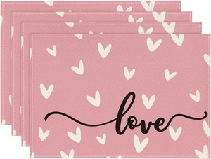 Detail of four-piece pink linen placemats with heart patterns and love calligraphy