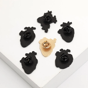 Set of six anatomical heart alloy brooches displayed on white cubes in a minimalist style