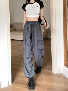 Detail view of deep grey high-waist cargo trousers with multiple pockets and elastic cuffs