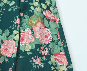 Close-up of vibrant floral print on deep green fabric with pink and yellow blossoms