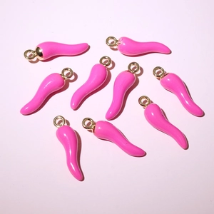 Macro view of pink enamel chili pepper pendants with golden loops for DIY jewelry making