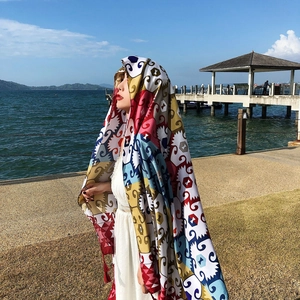Close-up of ethnic style red shawl with geometric patterns worn by a model at the beach