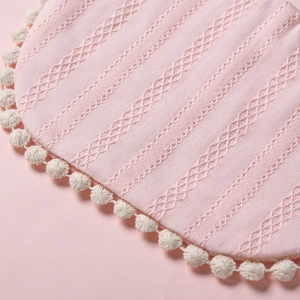 Détail d'un bavoir rose pour bébé avec bordure pompon et texture jacquard à rayures