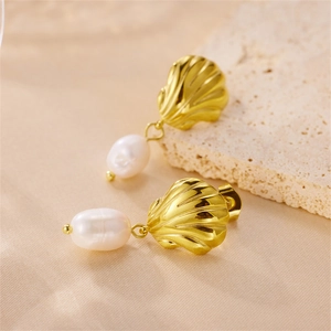 Elegant gold shell earrings with white pearls on a minimalist silk and stone background