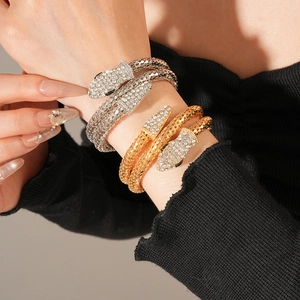 Close-up of a crystal-encrusted snake bangle in gold and silver finish on a wrist