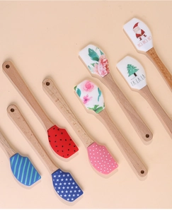 Macro detail of seven assorted silicone spatulas with festive prints and wooden handles