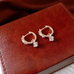 Gros plan de boucles d'oreilles fleur en or rose et zircon sur cuir marron