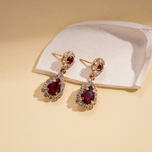 Detailed close-up of vintage style golden earrings with wine red rhinestone water droplets