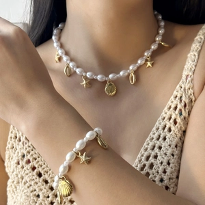 Close-up of summer beach jewelry set featuring pearl necklace and bracelet with gold charms