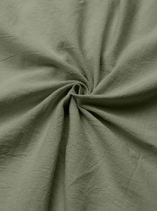Macro detail of olive green cotton linen fabric texture showing soft spiral drapes