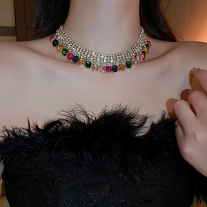 Close-up of luxury gold necklace featuring multi-color rectangular gemstones and tassels
