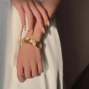 Bracciale minimalista dorato con dischi circolari testurizzati indossato da una donna