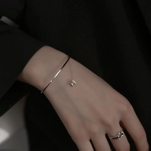 Detail showing a layered silver heart bracelet and hollow heart ring on a model