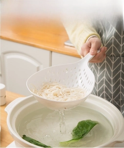 Close-up of a white nylon skimmer spoon straining noodles in a kitchen setting