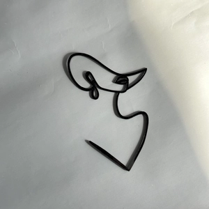 Dettaglio topper per torta con viso di donna in acrilico nero minimalista, arte lineare.