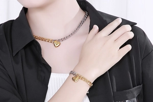 Close-up of gold and silver mixed Cuban chain heart necklace and bracelet set on a model
