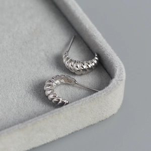 Macro shot of silver S925 sterling silver C-shaped hoop earrings with croissant texture