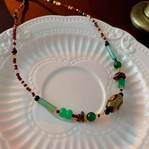Gros plan d'un collier ras du cou en perles colorées fait main avec une perle Dzi sur porcelaine