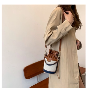 Brown leather and canvas bucket bag shown on shoulder in a bright minimalist room