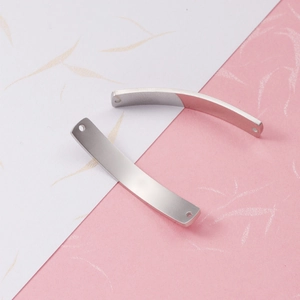 Close-up of two curved rectangular stainless steel connectors with holes for DIY jewelry