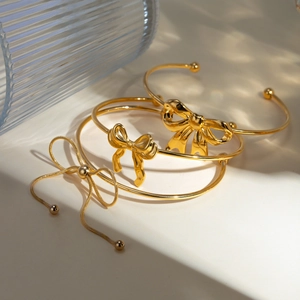 Detail showing gold bow bracelets and adjustable chain bracelet with polished finish