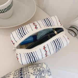 Detailed macro of open quilted makeup bag showing cherry prints and skincare storage