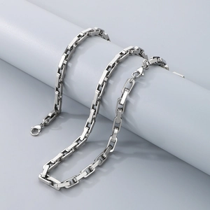 Detail of silver stainless steel thick square link chain draped on a grey cylindrical display